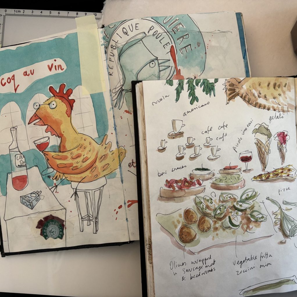 Two overlapping sketchbooks and a pot of murky paint water - sketches include images of a coq au vin a chicken drinking wine and a spread of Italian nibbles. all draing in pen and ink and a bit of watercolour